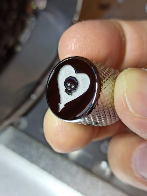 This is a deep engraved custom guitar knob with an Alkaline Trio skull logo